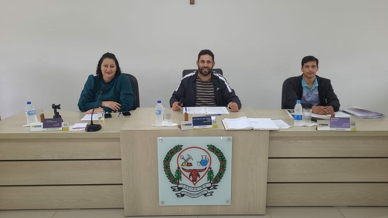 Foto da mesa diretora da Câmara, antes da reunião extraordinária, composta por, da esquerda para a direita, os vereadores Ana Paula, Luiz Carlos e Guilherme Jamil, olhando para a Câmera.