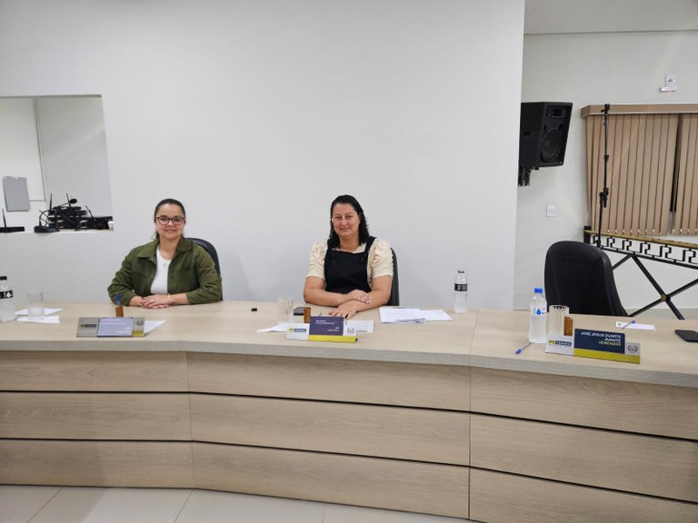 Da esquerda para direita, as Vereadoras Maria Eduarda e Ana Paula, em suas respectivas cadeiras, olhando para a Câmera.