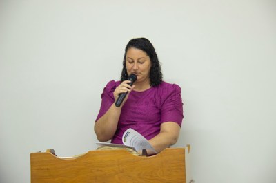 Vereadora Ana Paula em seu uso da tribuna, segurando um microfone e lendo a moção de congratulações